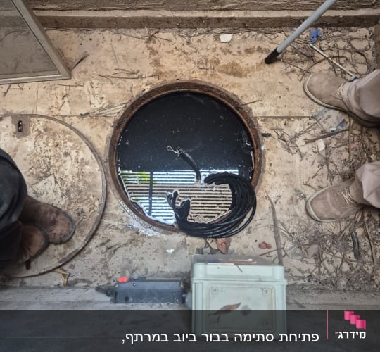 פתח ביוב עם כבל וכלי עבודה על הרצפה